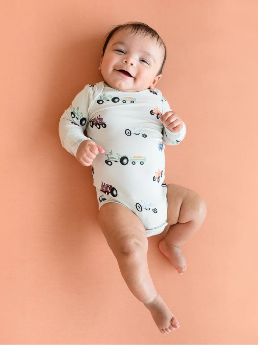Kyte BABY Cream Long Sleeve Bodysuit with Multicolor Tractor Print